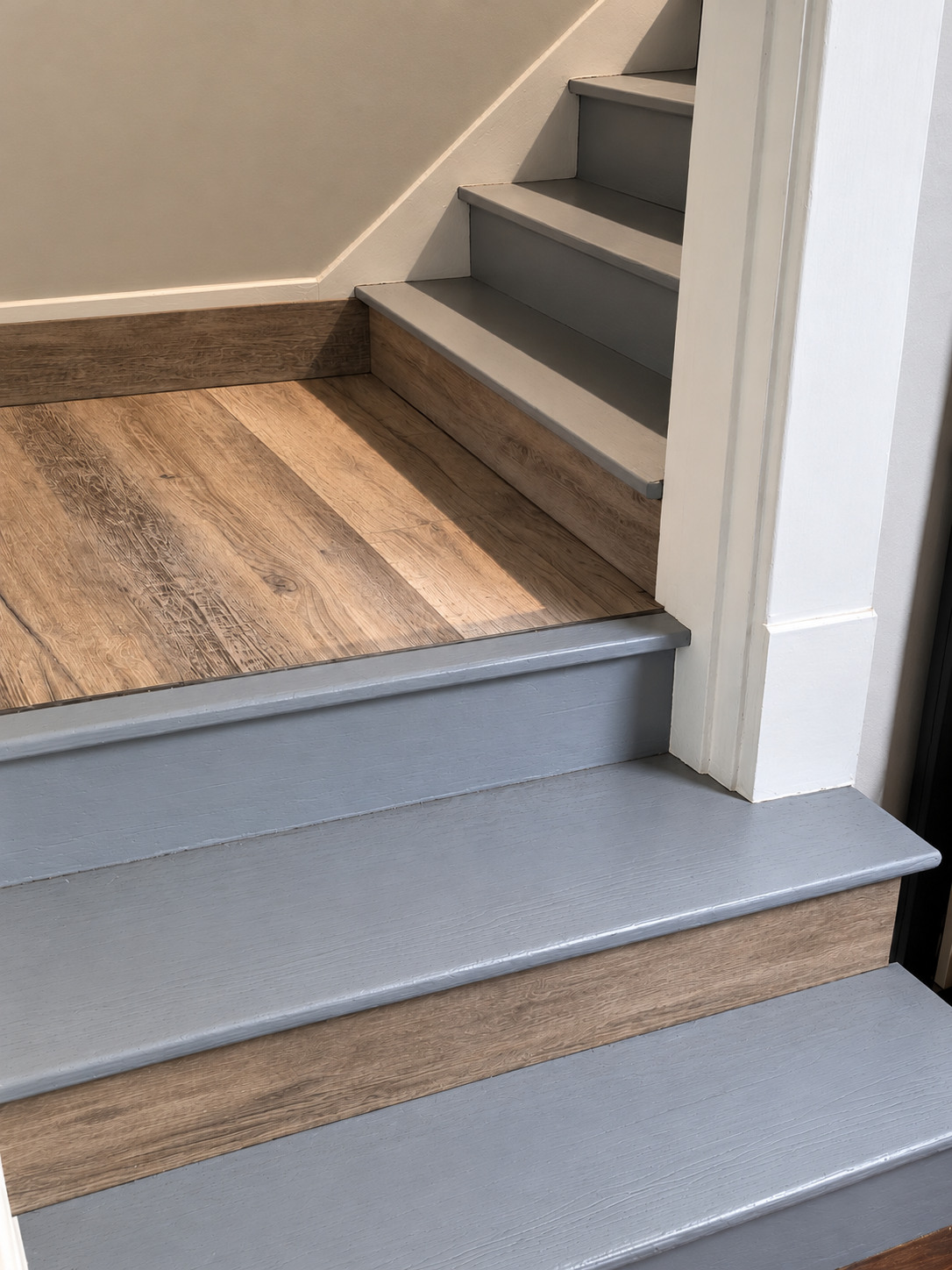 Wood-trimmed lower stair landing and painted gray stairs connecting the downstairs and upstairs living areas
